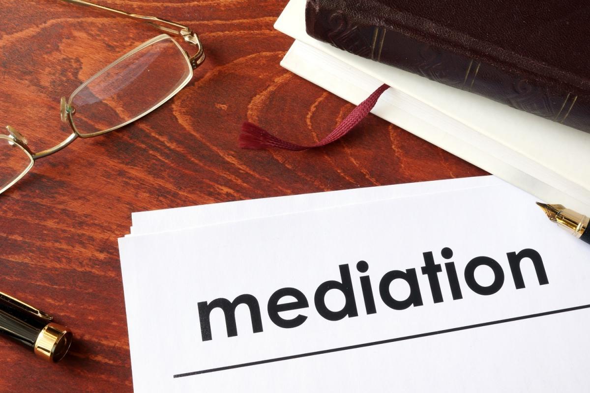 A document titled "Mediation" on a wooden desk with glasses and a journal nearby